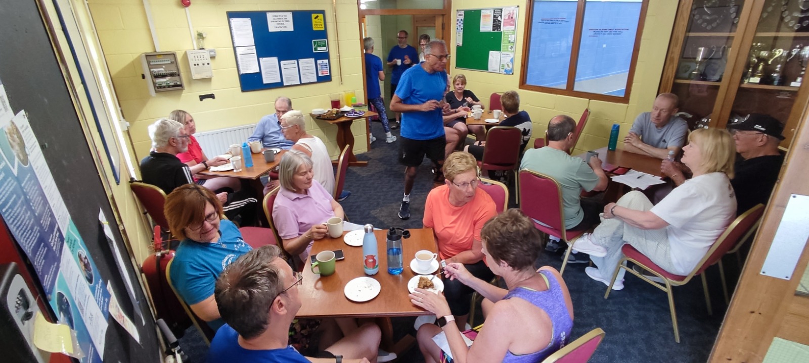 Pickleball players and volunteers sitting together around tables for tea and conversation after a session